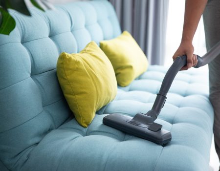 man using vacuum cleaner close up of man's hand cleaning couch using vacuum cleaner at home